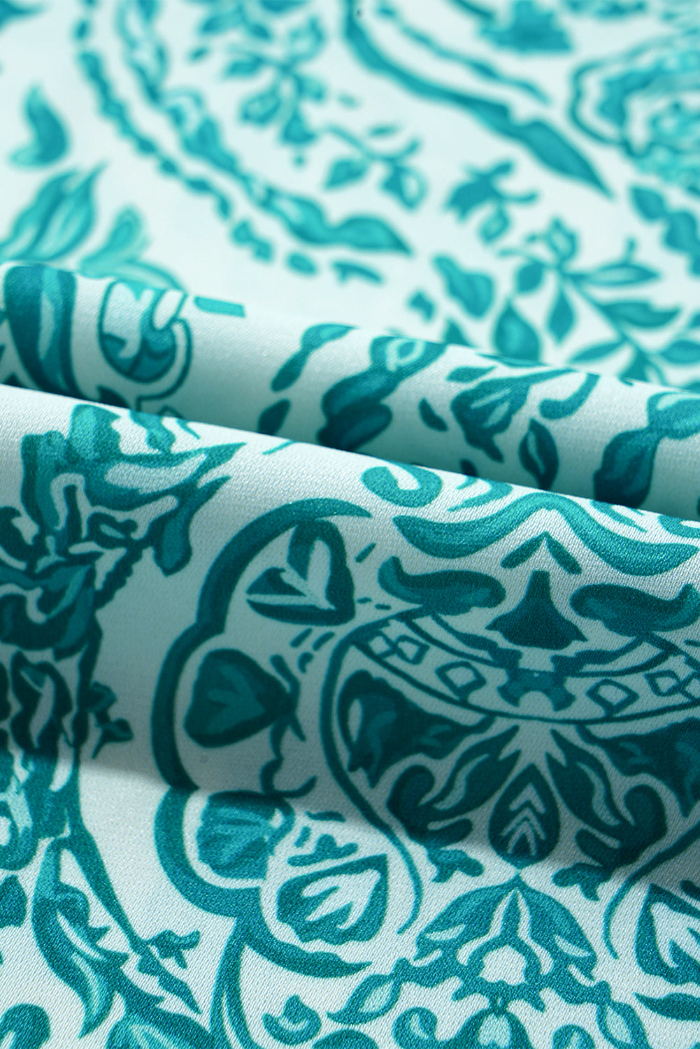 Green paisley print loose blouse with smocked cuffs and buttoned front, by ModestAndDevoted, made of lightweight polyester.