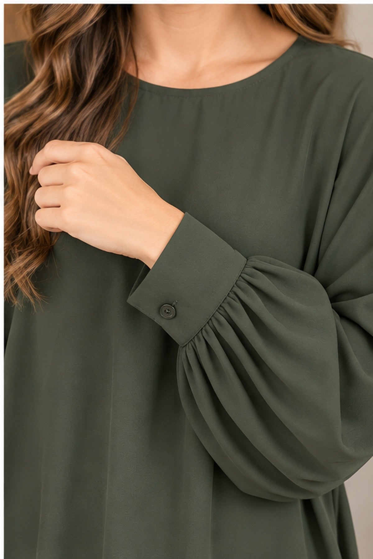 Closeup of gathered sleeve and button cuff on Andree olive blouse