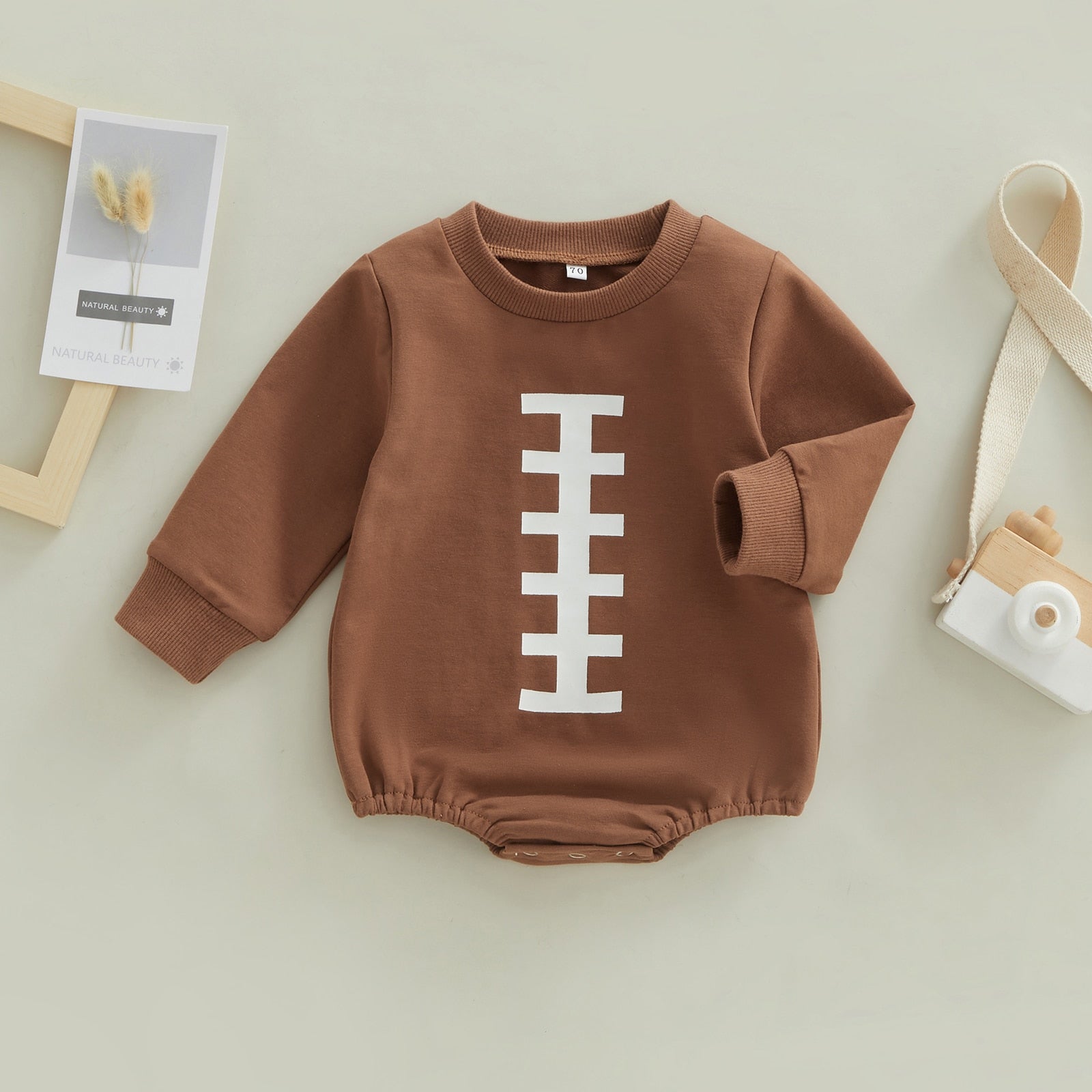 Baby boy girl jumpsuit by August + Willow featuring rugby football print, long sleeves, round neck, snap closure, bubble romper.