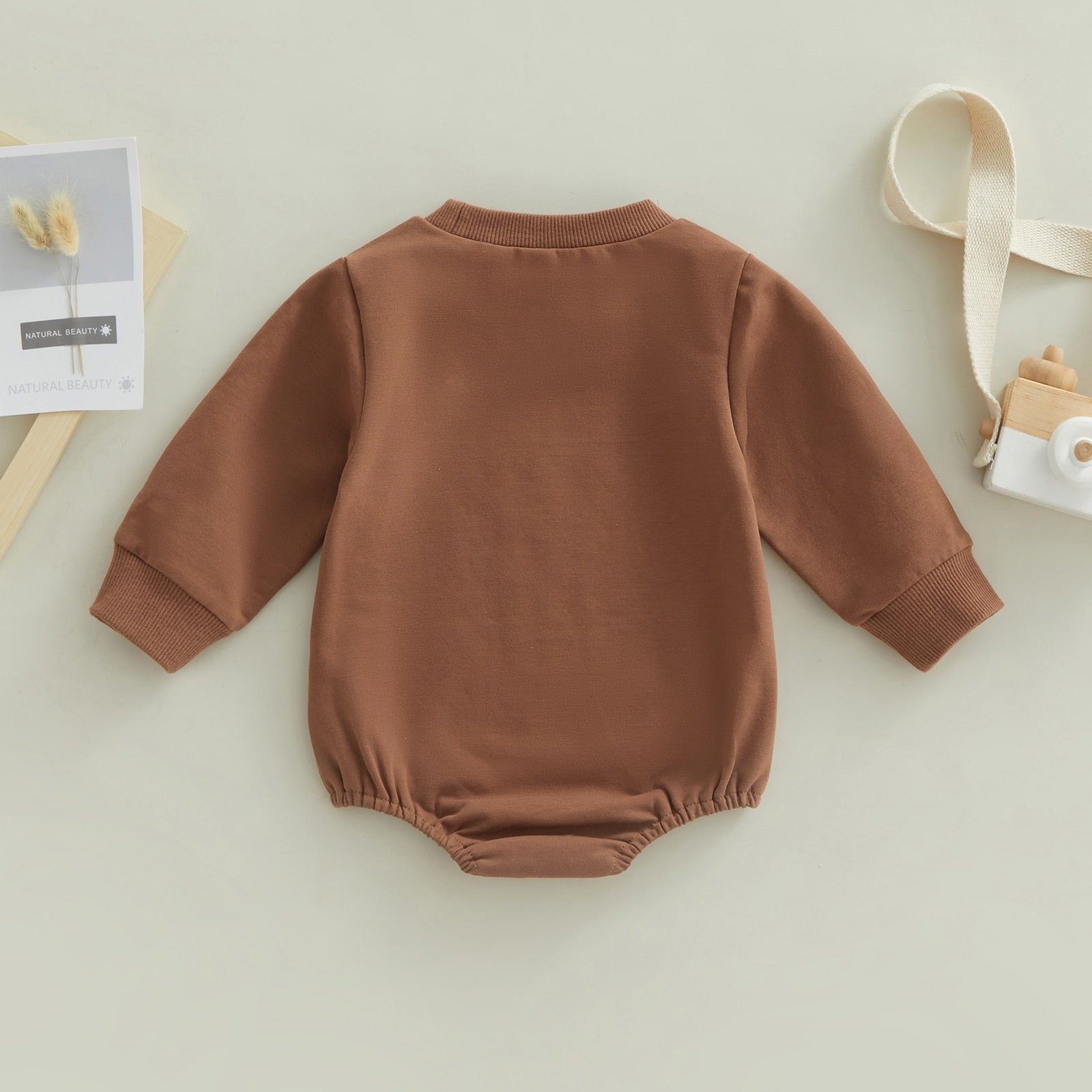 Baby boy or girl jumpsuit by August + Willow with rugby football print, long sleeves, round neck, and snap closure bubble romper.