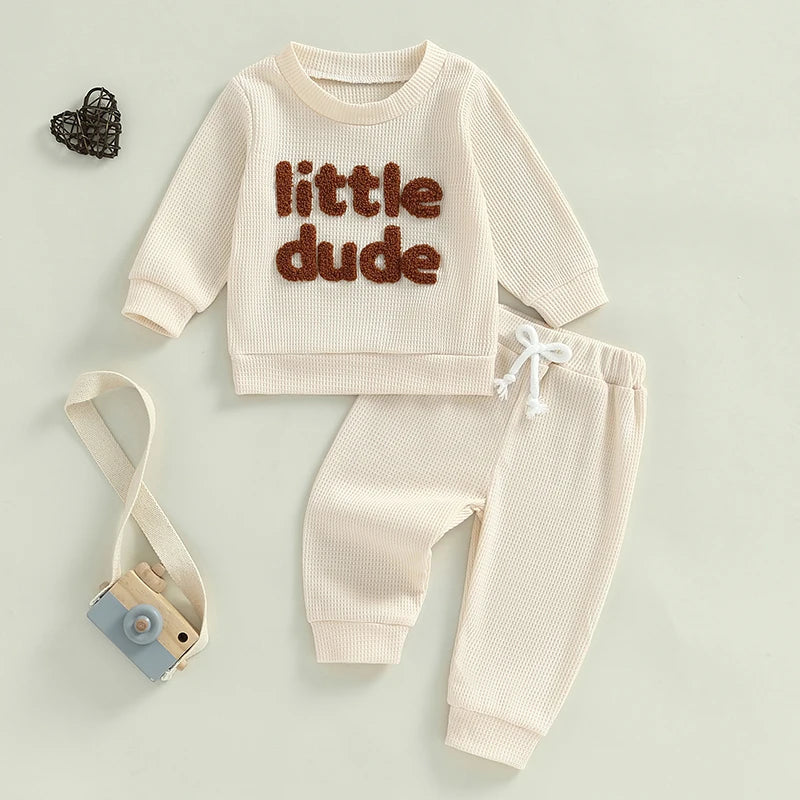 Baby toddler boys 2-piece waffle outfit with letter embroidery, long sleeve top, elastic waist solid pants by August + Willow, beige.
