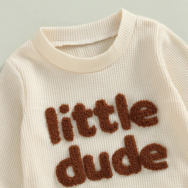 Baby boy 2-piece waffle outfit by August + Willow with letter embroidery, long sleeve top, elastic waist pants in beige for 12-18 months.