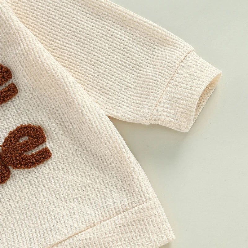 Baby toddler boys 2-piece waffle outfit by August + Willow with letter embroidery, long sleeve top and elastic waist solid pants in beige.