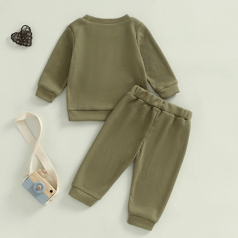Baby toddler boys beige 2-piece waffle outfit with letter embroidery, long sleeve top, and elastic waistband solid pants set by August + Willow.