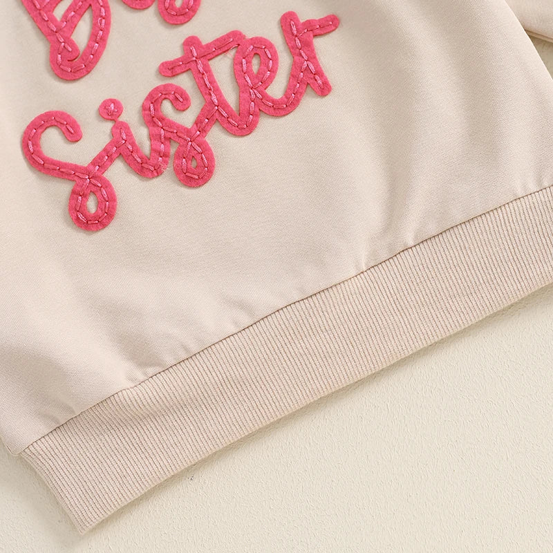 Beige toddler girls' long sleeve crewneck pullover from August + Willow with embroidered letter detail, loose fit, for big sisters.
