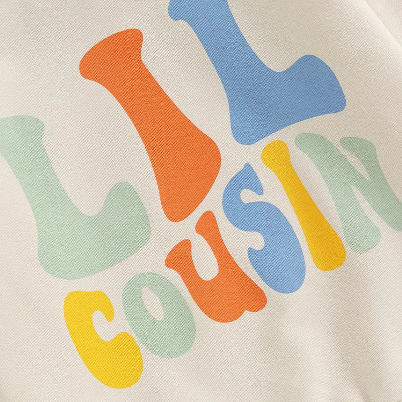 Baby and toddler girls and boys matching beige crewneck top with letter print and "Lil Cousin" design by August + Willow.
