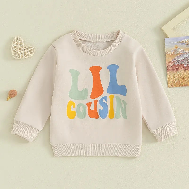 Baby and toddler girls and boys matching beige crewneck tops with letter print "Big Lil Cousin" by August + Willow.