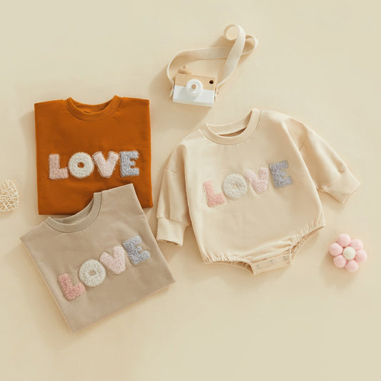 Light cream infant baby girl fall bodysuit by August + Willow with fuzzy letter love print, long sleeves, round neck, and bubble romper style.