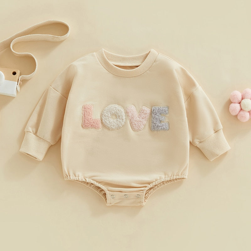 Baby girl fall bodysuit by August + Willow, fuzzy letter love print, long sleeves, round neck, cozy bubble romper in light cream.