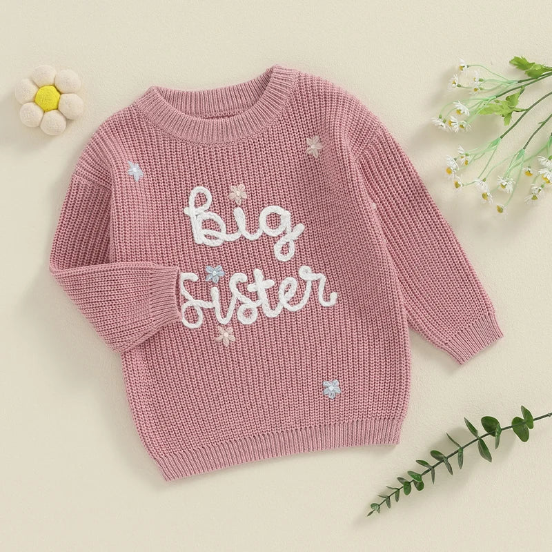 Light pink toddler girl sweater by August + Willow with long sleeves and embroidered letter design, cozy loose fit knit pullover.