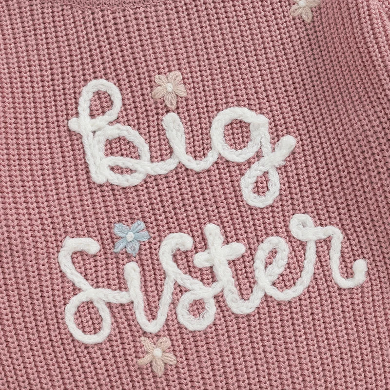 Light pink toddler girl sweater by August + Willow with long sleeves and embroidered letter design, cozy knit pullover for little girls.