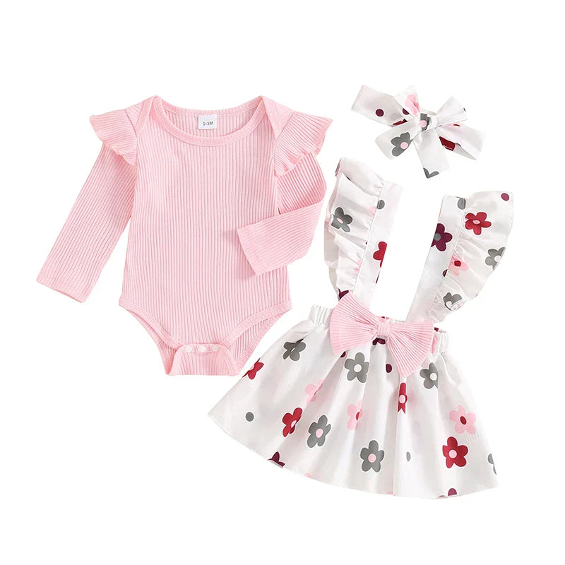 Baby girl fall outfit set with pink long-sleeve ribbed romper, flower print skirt, bow suspender, and headband by August + Willow.