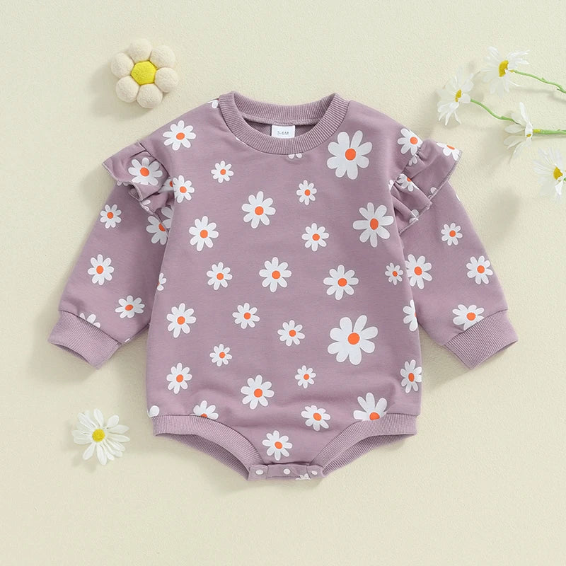 Baby girl in a purple daisy print bubble romper with long sleeves and round neck, from August + Willow, for 6-12 months.