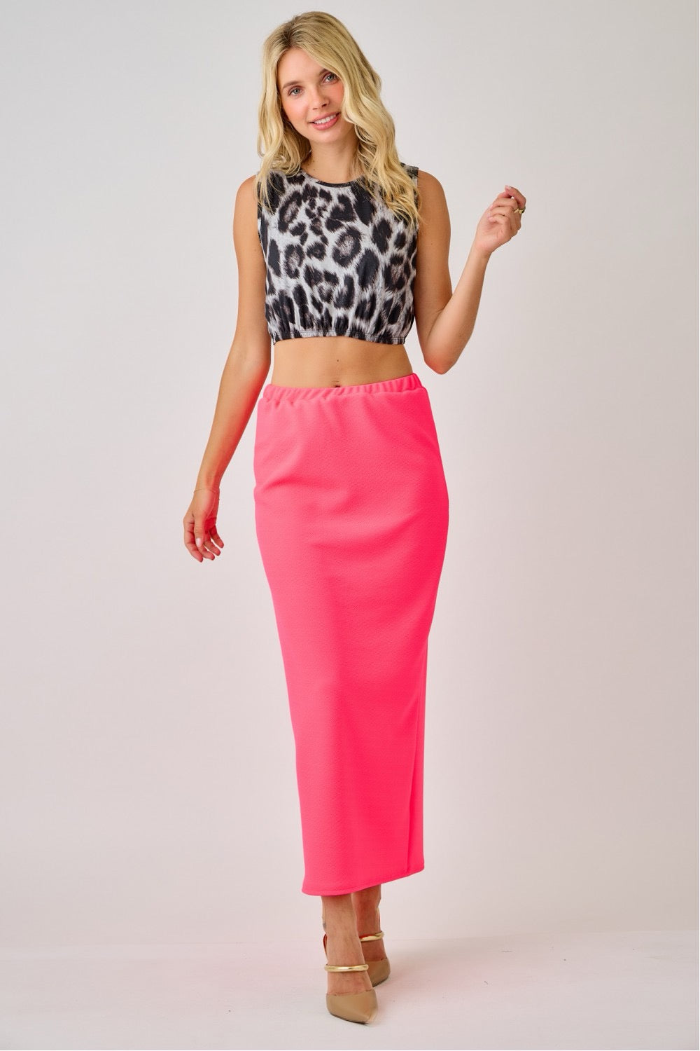 Lady wearing a neon fuchsia maxi length pencil skirt by Celeste Clothing, showcasing the fitted, elegant silhouette and vibrant color.