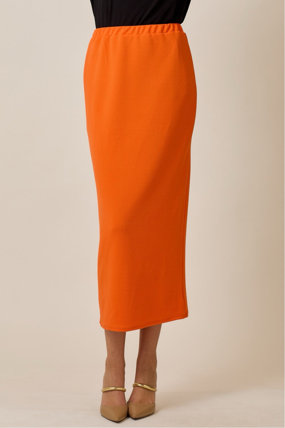 Orange maxi length pencil skirt for women by Celeste Clothing, shown in a close-up of the fitted design and vibrant fabric.
