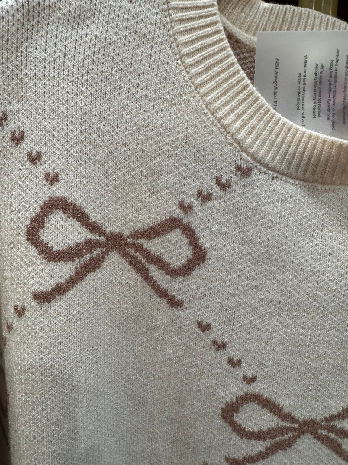 Close-up of taupe bow argyle woven knit on LovLov cream sweater