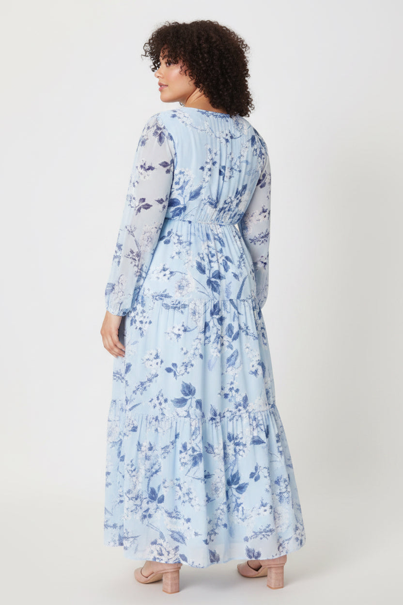 Blue denim floral Cadaval Mabel Maxi Dress by ModestAndDevoted displayed on hanger with flowing skirt and flower pattern.