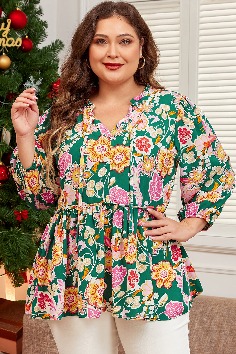 Plus size ModestAndDevoted green floral babydoll top with tied V-neck and long sleeves, made from lightweight polyester fabric.