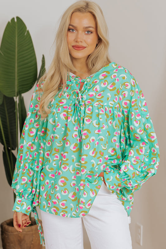 Green abstract printed lace-up lantern sleeve babydoll blouse from ModestAndDevoted, featuring a flowy silhouette and stylish design.