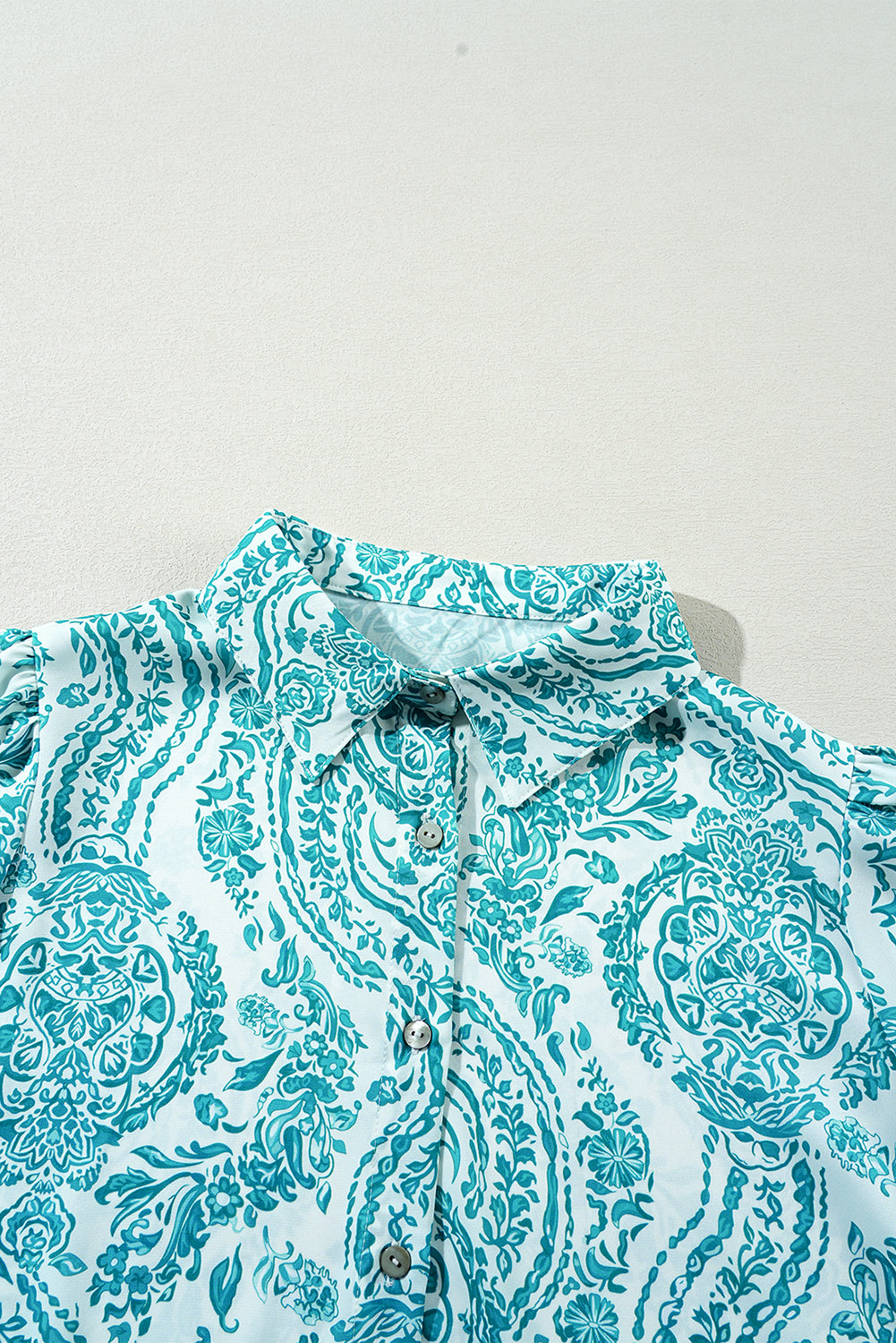 Green paisley print blouse by ModestAndDevoted featuring smocked cuffs, buttoned front, and loose fit in lightweight polyester fabric.