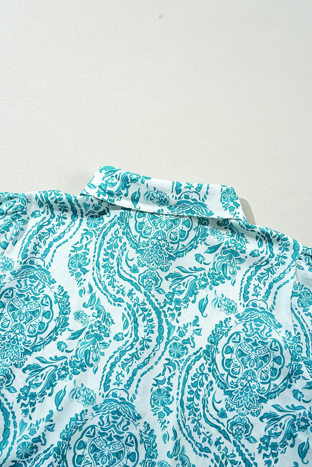 Green paisley print loose blouse with smocked cuffs and buttoned front, made by ModestAndDevoted, in polyester fabric.