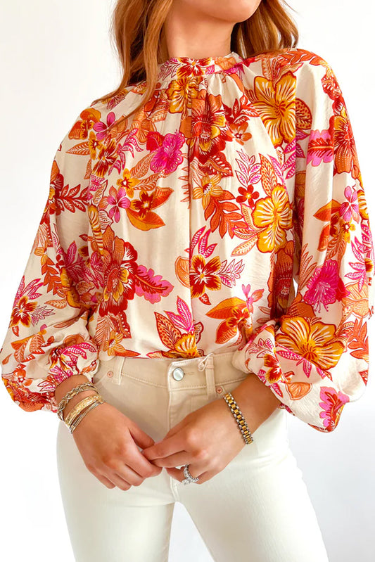 Orange floral print blouse by ModestAndDevoted featuring pearl buttons, keyhole neckline, and long puff sleeves, made of viscose and polyamide.