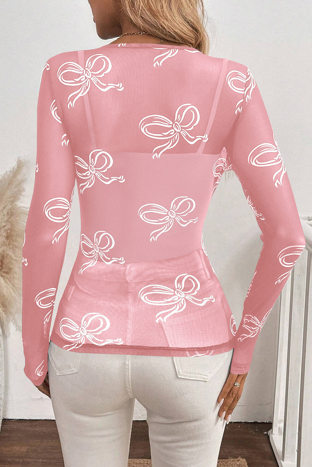 Pink round neck mesh top with bow print from ModestAndDevoted, long sleeve design, lightweight polyester and elastane fabric.
