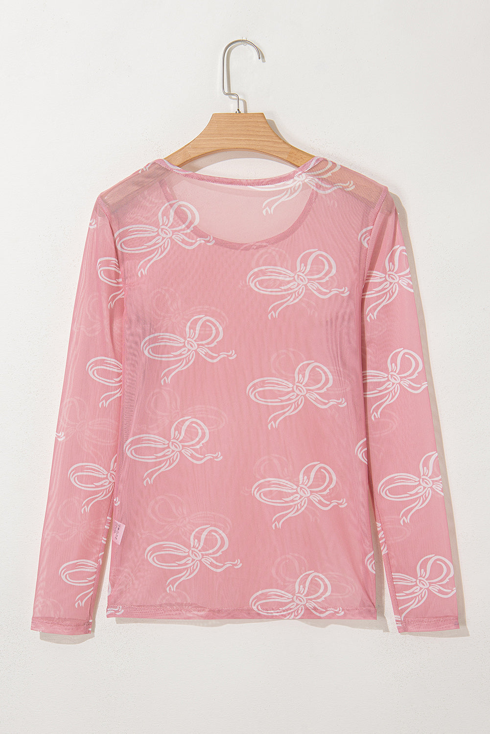 Pink round neck long sleeve mesh top with bow print from ModestAndDevoted, showcasing the soft fabric and stylish design.