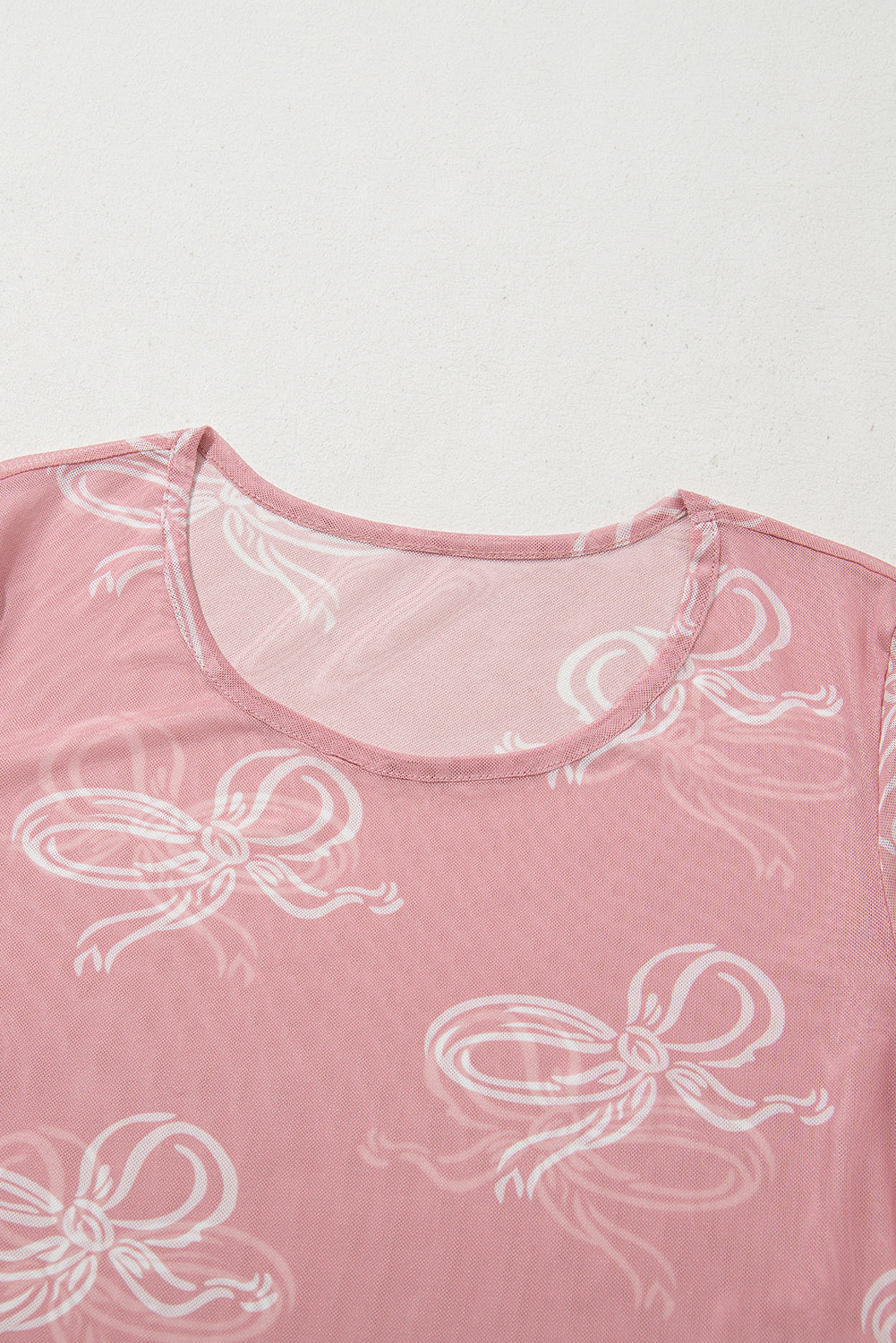 Pink round neck long sleeve mesh top with bow print by ModestAndDevoted, featuring a fitted design and sheer fabric.
