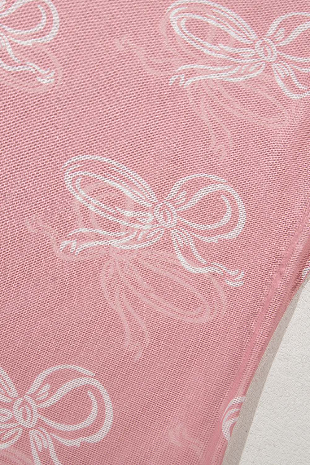 Pink round neck mesh long sleeve top with bow print from ModestAndDevoted, featuring a fitted design and sheer fabric.