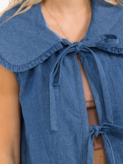 Front view of a sleeveless denim vest with a front tie and collar by ModestAndDevoted.