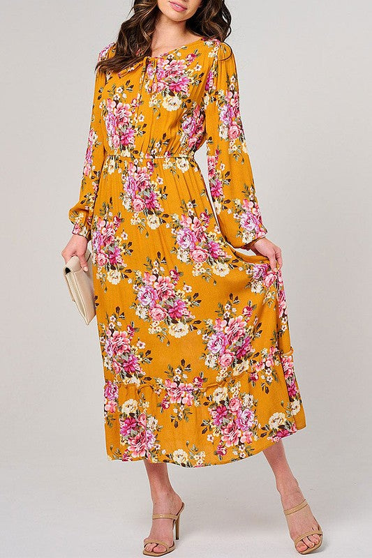 Long sleeve floral maxi dress by Rousseau with elastic waist in mustard, flowing fabric and vibrant floral pattern.
