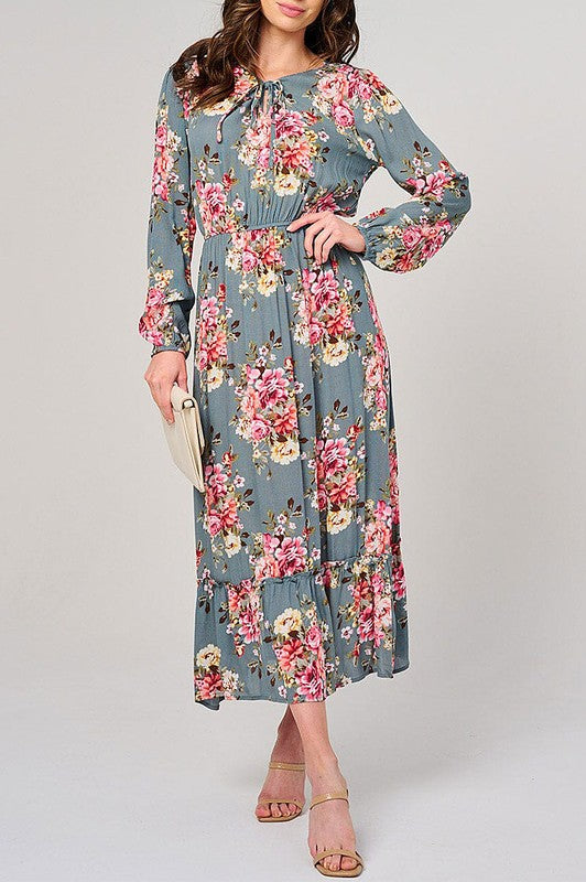 Long sleeve floral maxi dress in sage with elastic waist by Rousseau, featuring a flowing silhouette and vibrant floral pattern.